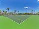 A vibrant green tennis court is surrounded by palm trees and blue skies in this amenity-filled community at 701 Maraviya Blvd, Nokomis, FL 34275