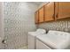 Convenient laundry room with geometric wallpaper, cabinets, and modern appliances at 7108 Playa Bella Dr, Bradenton, FL 34209
