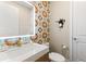 Modern powder room featuring decorative wallpaper, a stylish sink and vanity lighting at 7323 Great Egret Blvd, Sarasota, FL 34241