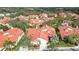 An aerial view displays well-maintained homes with red tile roofs nestled among mature trees in a lush community at 7344 Villa D Este Dr, Sarasota, FL 34238