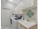Functional laundry room equipped with a washer, dryer, utility sink, and ample cabinet space at 7344 Villa D Este Dr, Sarasota, FL 34238
