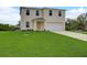 Two-story house with light beige siding, two-car garage, and a large grassy yard at 5128 Silver Bell Dr, Port Charlotte, FL 33948