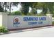 Entrance sign for Seminole Lakes Country Club, highlighting the community's name and logo amidst lush greenery at 26311 Seminole Lakes Blvd, Punta Gorda, FL 33955