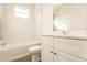 Clean bathroom with white cabinets, marble-look walls and bathtub at 1309 Nackman Rd, North Port, FL 34288