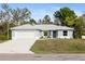 Charming single-story home with a two-car garage, neutral paint, and well-manicured landscaping at 825 Haleybury St, Port Charlotte, FL 33948