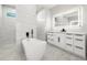 Modern bathroom featuring a standalone tub, sleek white vanity, and luxurious marble tile walls at 5823 Kumquat Ave, North Port, FL 34291