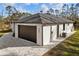 Side view of the home with a dark two-car garage door and paved driveway at 5823 Kumquat Ave, North Port, FL 34291
