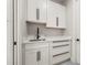 Well-lit laundry room with white cabinets, a sink, and modern black hardware at 5823 Kumquat Ave, North Port, FL 34291