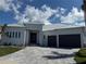 An elegant front exterior with a paved driveway, metal roof, black front doors and a three-car garage at 1426 Mineo Dr, Punta Gorda, FL 33950