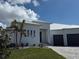An elegant front exterior with a paved driveway, metal roof, black front doors and a three-car garage at 1426 Mineo Dr, Punta Gorda, FL 33950