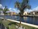 Picturesque waterfront with a canal, boat lift, and lush landscaping featuring swaying palm trees at 1426 Mineo Dr, Punta Gorda, FL 33950