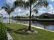 Beautiful waterfront property with lush green lawn, serene canal, and tropical palm trees at 1426 Mineo Dr, Punta Gorda, FL 33950