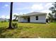 A view of the backyard shows the rear of the home, a concrete patio, and ample green space at 2163 Blaser St, Punta Gorda, FL 33980