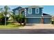 Two-story house featuring a blue exterior, stone accents, and a three-car garage at 2736 Suncoast Lakes Blvd, Punta Gorda, FL 33980