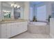 This bathroom offers granite countertops, double sinks, a soaking tub, and natural light at 15240 Spanish Point Dr, Port Charlotte, FL 33981