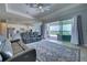 A well-lit living room featuring a large area rug, modern ceiling fan, and sliding glass doors to the outdoor pool area at 15240 Spanish Point Dr, Port Charlotte, FL 33981