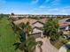 Stunning aerial view of a home with a tile roof, brick driveway, tropical landscaping, and lush green lawns at 13948 Miranese St, Venice, FL 34293