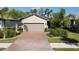 Single-story home with light-colored siding, brick driveway, and lush landscaping at 2555 Brassica Dr, North Port, FL 34289