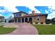 Inviting two-story home with a three-car garage, arched entryway, and red brick-lined driveway at 56 Colony Point Dr, Punta Gorda, FL 33950