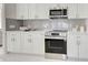 Modern kitchen features white cabinets, stainless steel appliances, gray backsplash, and ample counter space at 9310 Rosebud Cir, Port Charlotte, FL 33981