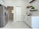 Walk-in pantry features white cabinets, floating shelves, and sleek tile flooring, offering style and functionality at 9310 Rosebud Cir, Port Charlotte, FL 33981