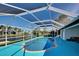 Sparkling screened-in pool with bright blue pool deck and canal view is perfect for relaxing and entertaining at 9310 Rosebud Cir, Port Charlotte, FL 33981