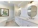 Bright bathroom featuring double vanity with white cabinets, marble countertop, brass fixtures, and a large framed picture at 611 W Olympia Ave, Punta Gorda, FL 33950