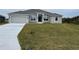 Newly constructed one-story home featuring a gray exterior, two-car garage, and a spacious lawn at 10045 Bay State Dr, Port Charlotte, FL 33981