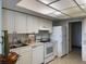 White kitchen cabinets and appliances, view to hallway at 3100 Harbor Blvd # 116, Port Charlotte, FL 33952