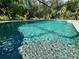 Aqua-colored pool with patterned bottom, surrounded by lush foliage at 4767 Maurbach Ter, North Port, FL 34286