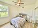 Cozy bedroom with ceiling fan, a large window overlooking the backyard, and wood-look tile floors at 3140 Sweet Gum Dr, Punta Gorda, FL 33982