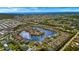 Stunning aerial view of a waterfront community featuring homes encircling a sparkling lake, ocean in background at 24723 Rio Villa Lakes Cir, Punta Gorda, FL 33950