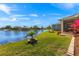 Picturesque backyard with lush lawn, manicured landscaping, brick accents and beautiful water views at 24723 Rio Villa Lakes Cir, Punta Gorda, FL 33950