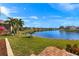 Enjoy serene water views from this beautiful backyard with lush lawn, colorful foliage and brick accents at 24723 Rio Villa Lakes Cir, Punta Gorda, FL 33950