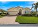 Charming home with a brick driveway, lush green lawn, and well-manicured landscaping at 24723 Rio Villa Lakes Cir, Punta Gorda, FL 33950