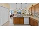 Functional kitchen featuring a double sink, dishwasher, wood cabinetry, and view to the living room at 24723 Rio Villa Lakes Cir, Punta Gorda, FL 33950
