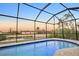 Evening view of a refreshing pool within a screened enclosure at 13164 Amaryllis Cir, Port Charlotte, FL 33981
