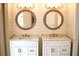 Bathroom with double sinks, white cabinets, dual round mirrors, and modern vanity lighting at 956 Harbor Town Dr, Venice, FL 34292