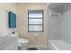 Well-lit bathroom with tub and toilet featuring tiled floors and a frosted window at 3936 Crooked Island Dr, Punta Gorda, FL 33950