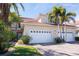 Tan two-story home with white garage doors, landscaping, and palm trees at 143 Tropicana Dr # 1012, Punta Gorda, FL 33950