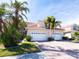 Tan two-story home with white garage doors, landscaping, and palm trees at 143 Tropicana Dr # 1012, Punta Gorda, FL 33950