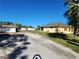 Wide shot of the house showing driveway and detached garage in the background under a bright blue sky at 12070 Surrey Ave, Port Charlotte, FL 33981