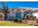 Front entry with arched entryway, teal door, and stone landscaping at 831 Via Tunis, Punta Gorda, FL 33950