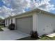 A detached single-car garage with a long driveway, a neutral exterior, and a well-kept lawn with minimal landscaping at 20399 Ladner Ave, Port Charlotte, FL 33954