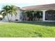 Landscaped front yard with a lush green lawn, mature palm trees, and a view of the home's facade at 3448 Nighthawk Ct, Punta Gorda, FL 33950