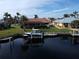 Picturesque waterfront property featuring a private dock, boat lift, and lush landscaping at 3448 Nighthawk Ct, Punta Gorda, FL 33950