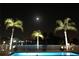 Inviting pool scene at night with palm trees and lighting at 1345 Mediterranean Dr # A203, Punta Gorda, FL 33950