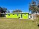 Backyard with large grassy area, and the vibrant green exterior of the single-story home at 30431 Holly Rd, Punta Gorda, FL 33982