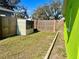 Backyard showcasing shed, fence, lush lawn, and the bright green exterior of the single-story home at 30431 Holly Rd, Punta Gorda, FL 33982