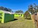 Spacious backyard with a green shed, lush lawn, and the bright green home exterior at 30431 Holly Rd, Punta Gorda, FL 33982